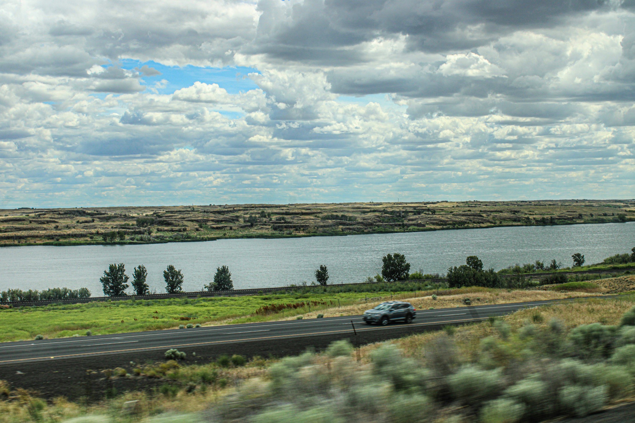 An SUV driving on a two-lane highway through the open plains of western Kansas.